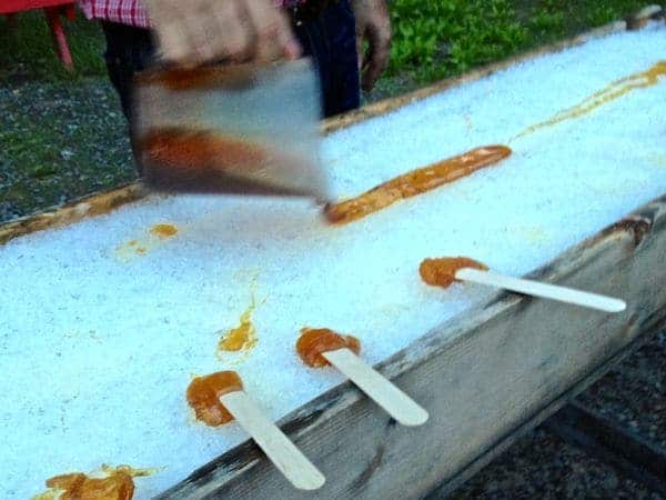 Making maple syrup on a stick by rolling it in snow.