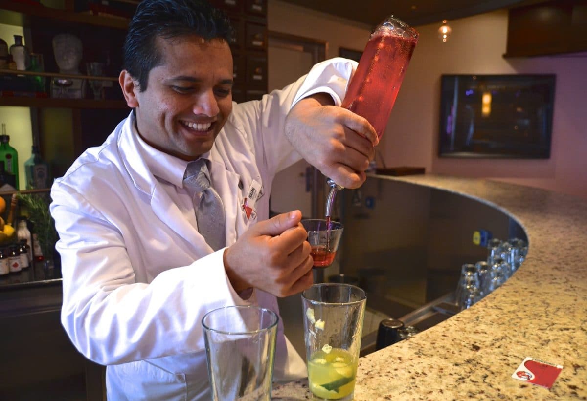 A bartender at a Carnival Alchemy bar mixes up a passenger's cocktail concoction.