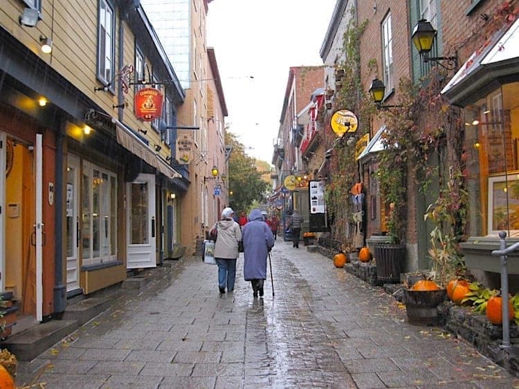 Two women in raincoats strolling through Old Quebec.