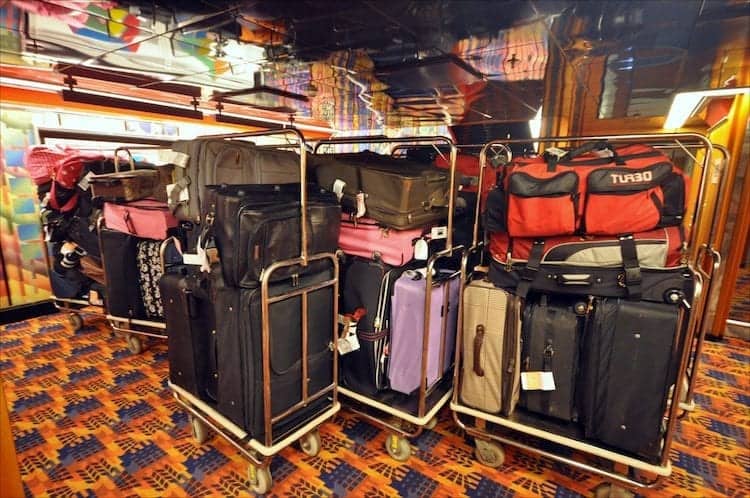 Luggage piled onto carts parked in ship's hallway.