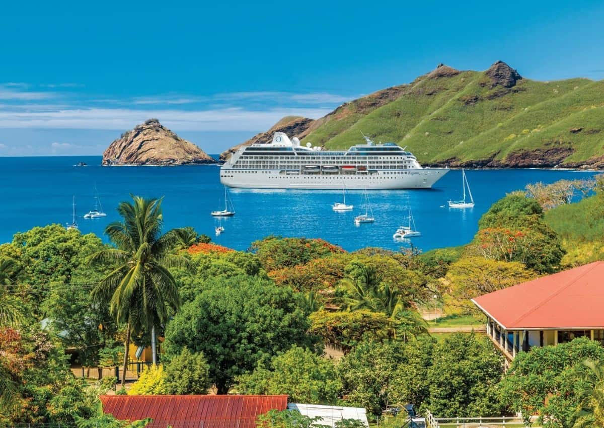Cruise Ship Anchored in a harbor in the Caribbean with a mountain behind.